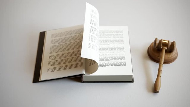 Law book opens beside wooden gavel to reveal Latin legal maxims