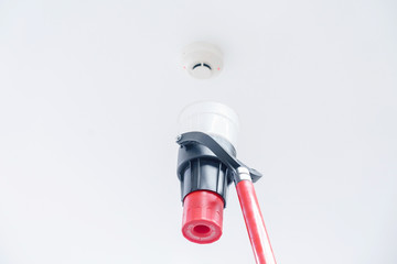 Automatic smoke detector fire alarm head on the ceiling. The smoke detector is triggered by a trickle of dum, the red indicator lights up