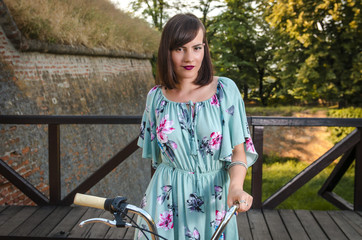 Pretty woman portrait, summer dress and holding bicycle handle 