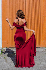 Beautiful young woman in a long red evening gown with a train