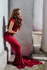 Beautiful young woman in a long red evening gown with a train