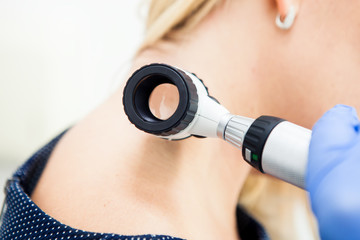 Examination of the patient's skin by a dermatologist using a dermatoscope