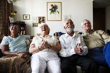 Group of senior friends sitting and watching tv together - obrazy, fototapety, plakaty