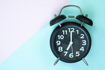 Vintage alarm clock on sweet pastel colored paper top view, background texture, pink, purple, yellow, beige, green and blue colour.