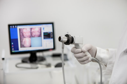 Videorecdoscope for visual diagnosis in the hand of a proctologist on the background of an unsharpened monitor.