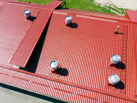 new red metal warehouse roof with installed pipes of ventilation systems