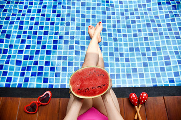 Beautiful bikini girl relaxing in swimming pool, Legs of woman in water, Fresh watermelon and summer party holiday.