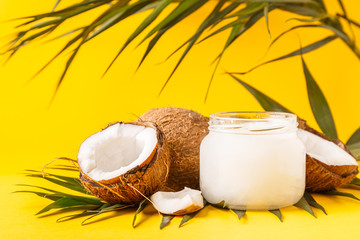 Coconut oil and coconuts on a bright pastel background.