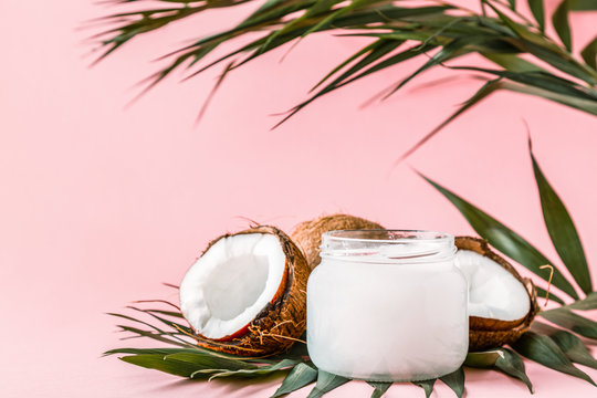 Coconut oil and coconuts on a bright pastel background.