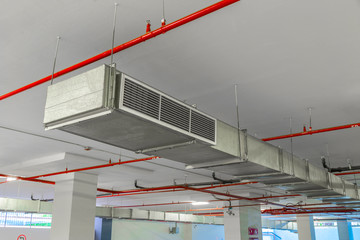 Industrial air duct ventilation equipment and pipe systems installed on industrial building ceiling.
