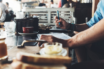 Entrepreneur working on his project at street cafe, writing down plans close-up