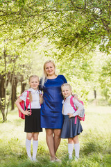 Fototapeta premium happy mom hugging two daughters Schoolgirls outdoors