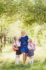 happy girls in school uniform hugging mom outdoors