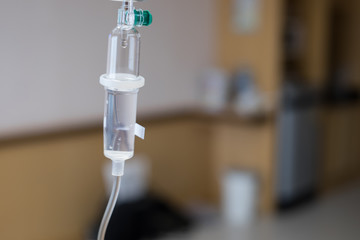 Close up saline drip for patient in hospital room. Patient on the bed.