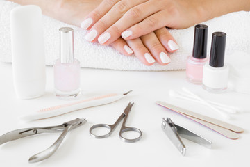 Obraz na płótnie Canvas Young, perfect, groomed woman's hands with white nails on the towel. Set of nails tools on the table. Hands care. Manicure, pedicure beauty salon.