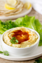 Hummus with olive oil and paprika, served with pita, lemon and lettuce leaves.