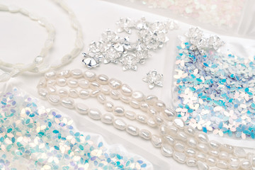 Materials for creative work on a white background. Ivory pearls and light blue sequins