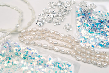 Materials for creative work on a white background. Ivory pearls and light blue sequins