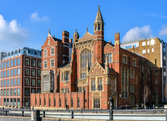 Red brick Victorian house with mullioned windows and golden ornaments at Victoria Embankment street, London
