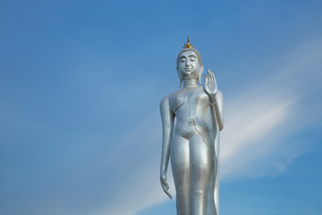 Fototapeta na wymiar Walking Buddha image silver on a beautiful sky background.