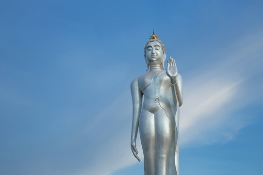 Walking Buddha image silver on a beautiful sky background.