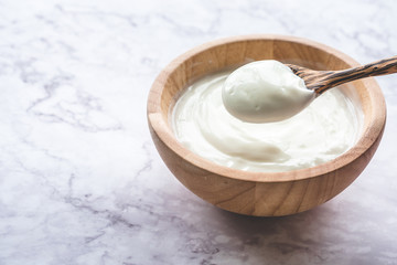 Fototapeta na wymiar Yogurt in wooden bowl on marble table