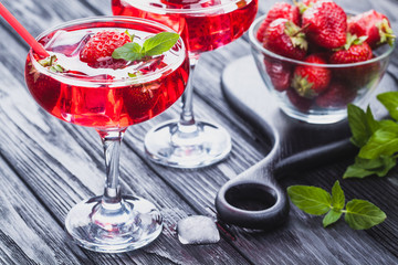 strawberry cocktail with ice and fresh mint on a black wooden table
