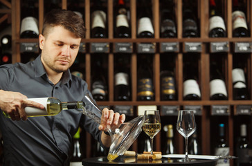 Serious sommelier pouring white wine in decanter