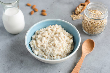 Steel cut oats, oatmeal porridge in bowl. Healthy breakfast on grey concrete table background
