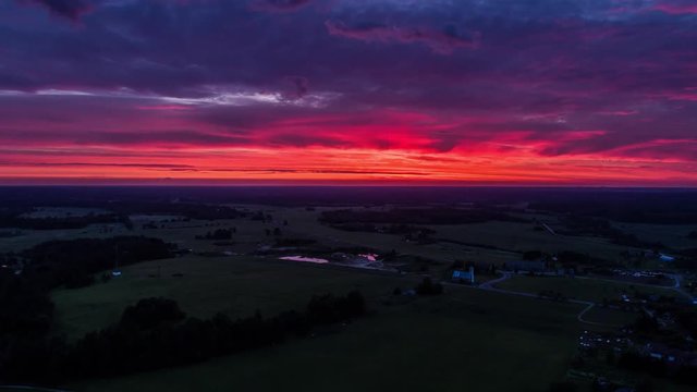 Aerial view of green fields with clouds above at sunset. Drone sunset timelapse footage. Summer nature  landscape.