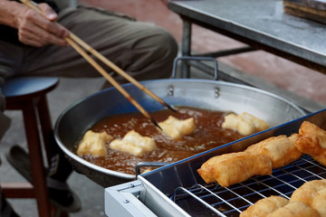   Deep fried dough in tray with blurred man fring dough for sell in morning market of Thailand