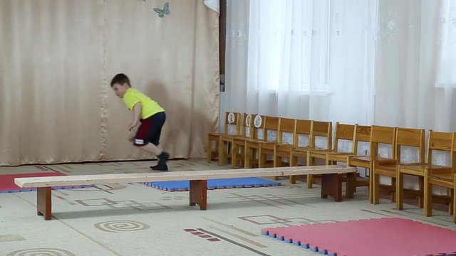 Sportsman trains somersaults on tatami and a jump through the bench