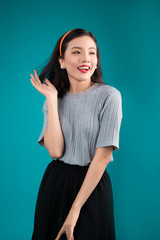 Smiling lovely asian woman dressed in pin-up style dress over blue.