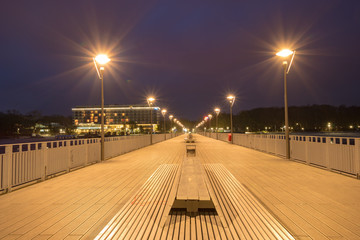 Fototapeta na wymiar Illuminated pier by the sea at night