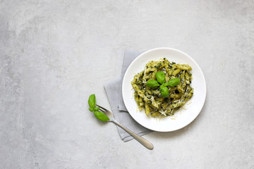 Pesto pasta. Pasta Penne in a white plate on gray background.