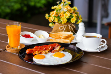 Breakfast with fried egg, bacon, coffee and orange juice crushed
