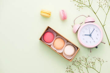 Colorful macaroons and rose flowers with gift box on wooden table. Sweet macarons in gift box. Top view