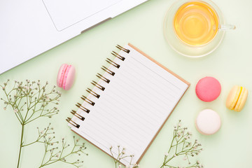 White desk with colorful macaroons, keyboard and open notebook.
