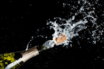 Celebration of birthday, anniversary or Christmas theme. Explosion of splashing champagne sparkling wine with flying cork out of the bottle on black background. © Nikolay N. Antonov