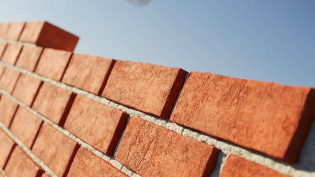 The clay brick wall being build at clear blue sky background. Loopable