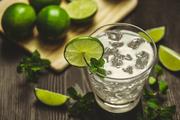 Glass of water with lime, ice and mint. Isolated on wooden background.