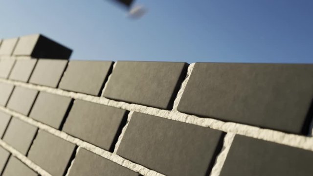 The clinker brick wall being build at clear blue sky background. Loopable