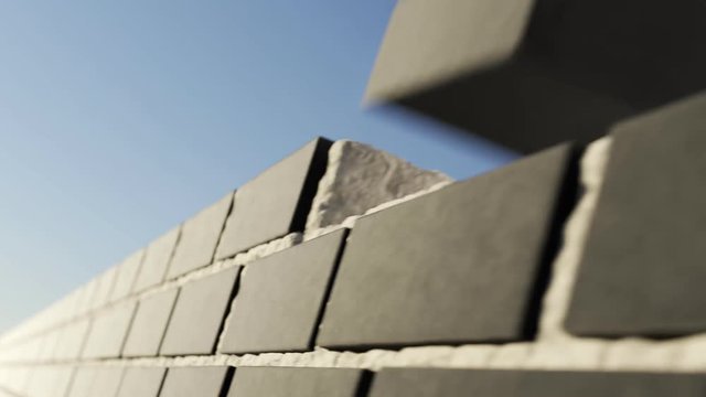 The clinker brick wall being build at clear blue sky background. Loopable
