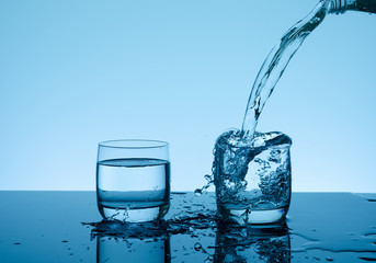 Creative splashing water in the glass on blue background