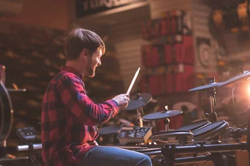 Keuken foto achterwand Muziekwinkel Jonge man die drumt in een muziekwinkel