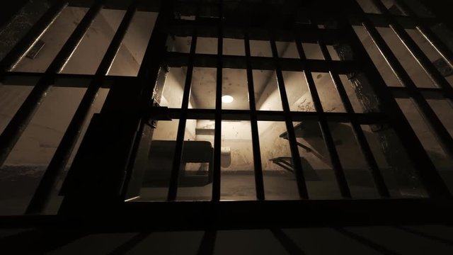 Prison cell metal gate swinging open in dark grimy interior room
