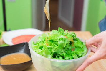 Female hands adding sauce to lettuce from lettuce leaves. Home kitchen. Tasty healthy and healthy food