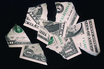Torn ripped devalued one dollar bank note on a black background.