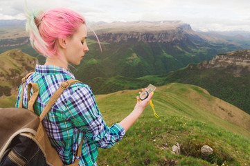 A hipster girl traveled with a blogger in a plaid shirt and with multi-colored hair using a compass...