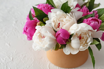 Box with beautiful peony flowers on white table